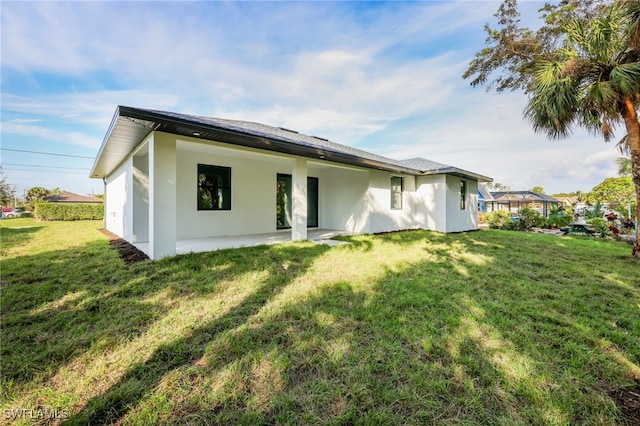 back of house with a patio area and a lawn