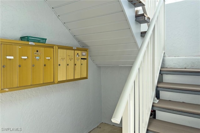 staircase with vaulted ceiling and a mail area