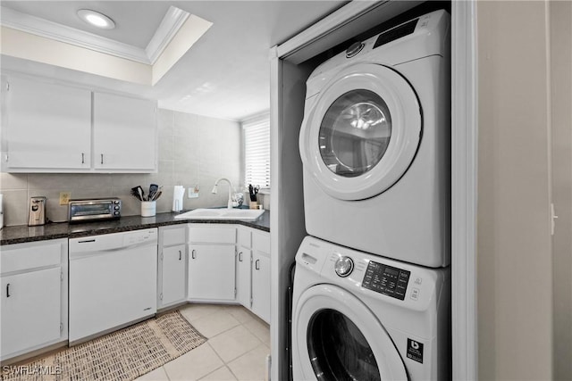 laundry area featuring sink, ornamental molding, stacked washer and dryer, and light tile patterned floors