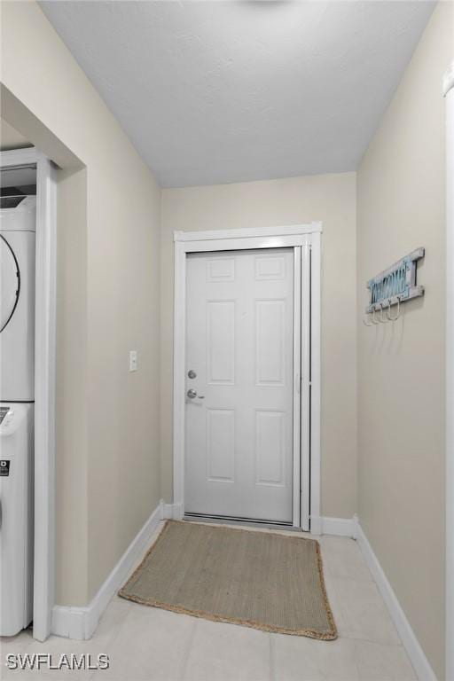 entryway featuring stacked washer and dryer and light tile patterned floors