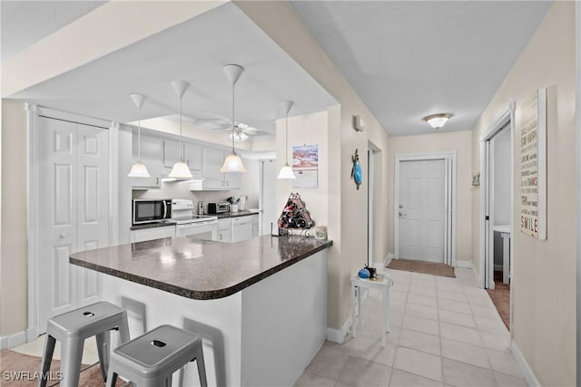 kitchen with pendant lighting, a kitchen breakfast bar, white electric stove, kitchen peninsula, and white cabinetry