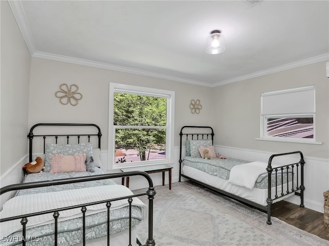 bedroom featuring a wainscoted wall, ornamental molding, and wood finished floors