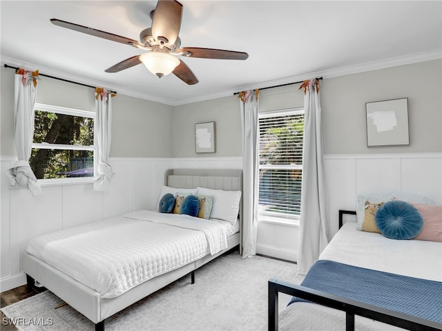 bedroom with a ceiling fan, wainscoting, and crown molding