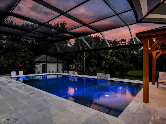 pool at dusk with glass enclosure, a patio area, an outdoor structure, and an outdoor pool