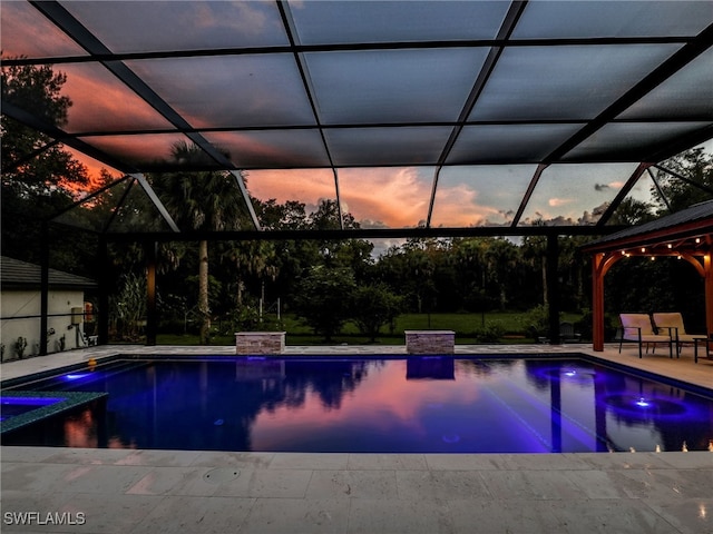 pool at dusk with a patio and a lanai