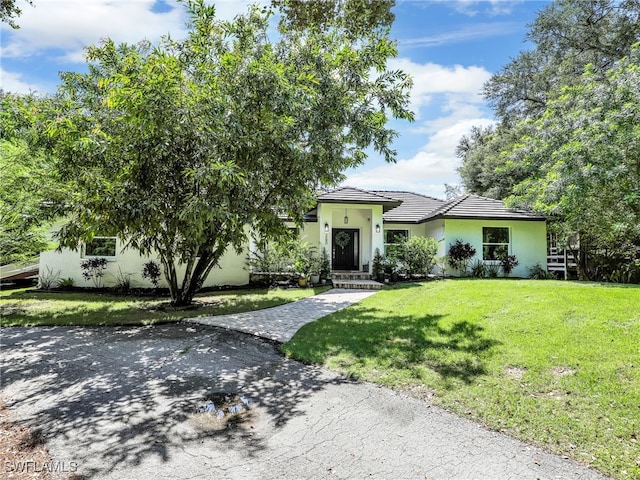 view of front of property with a front lawn, a tile roof, and stucco siding