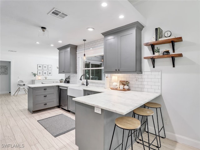 kitchen with gray cabinets, visible vents, backsplash, dishwasher, and a peninsula