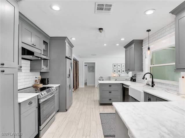 kitchen with stainless steel appliances, visible vents, gray cabinetry, a sink, and under cabinet range hood