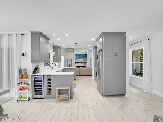 kitchen featuring freestanding refrigerator, beverage cooler, a peninsula, and gray cabinetry