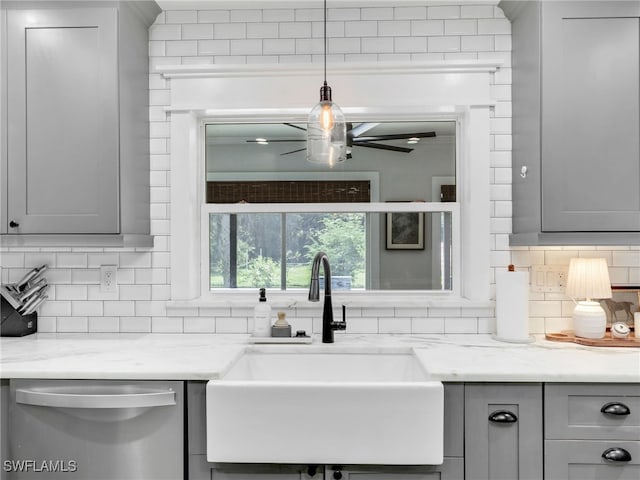 kitchen featuring decorative backsplash, gray cabinetry, a sink, and stainless steel dishwasher