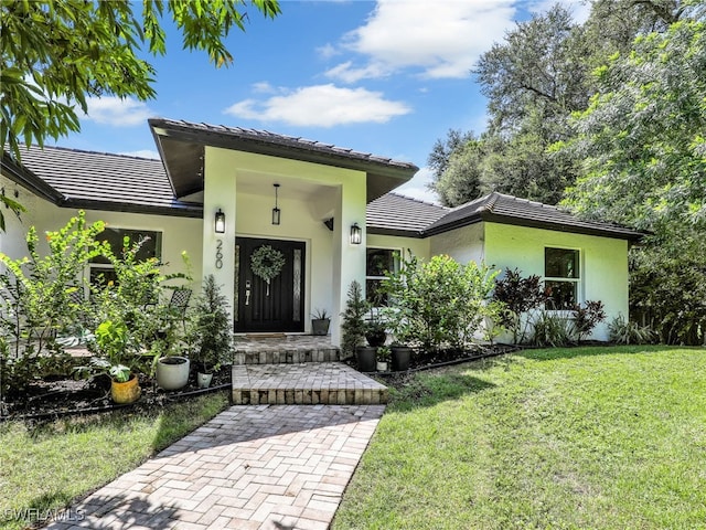 view of front of property with a tiled roof, a front lawn, and stucco siding