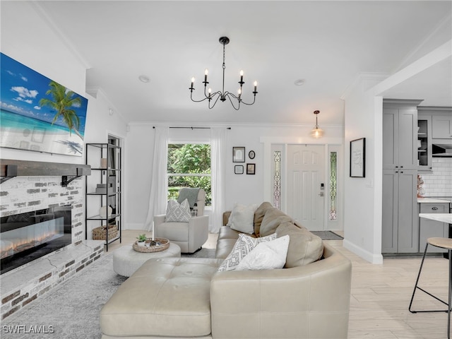 living room featuring a notable chandelier, a fireplace, baseboards, light wood-type flooring, and crown molding