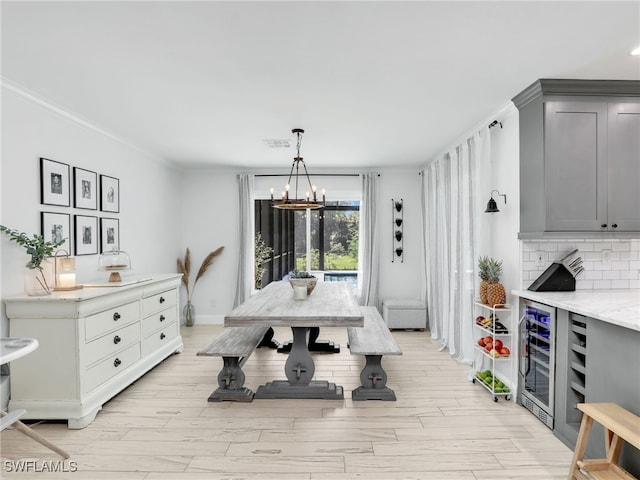 dining area featuring light wood-style floors, beverage cooler, visible vents, and crown molding