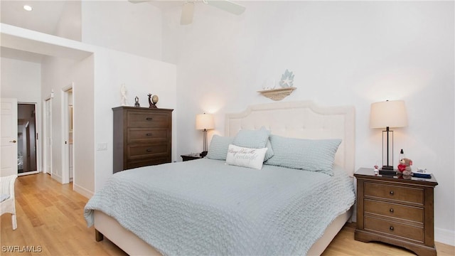 bedroom featuring ceiling fan, a high ceiling, and light wood-type flooring