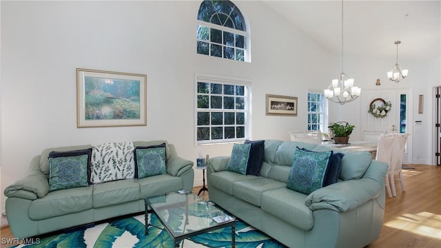 living room featuring hardwood / wood-style flooring, high vaulted ceiling, and a chandelier