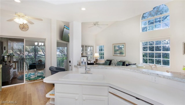 kitchen featuring sink, a healthy amount of sunlight, light hardwood / wood-style flooring, vaulted ceiling, and white cabinets