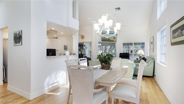 dining room featuring a notable chandelier, light hardwood / wood-style floors, and a high ceiling