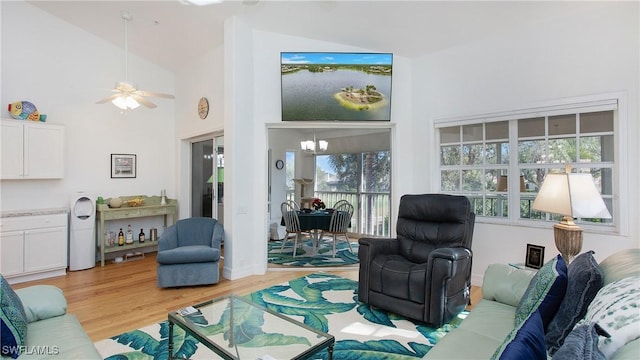 living room featuring ceiling fan with notable chandelier, light hardwood / wood-style floors, and high vaulted ceiling