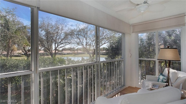 sunroom / solarium featuring plenty of natural light, ceiling fan, and a water view