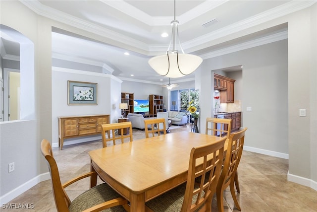 dining area with a raised ceiling, crown molding, and sink