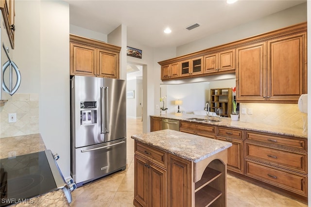 kitchen featuring decorative backsplash, appliances with stainless steel finishes, light stone counters, sink, and light tile patterned floors