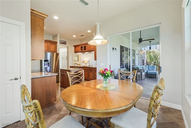 tiled dining area with ceiling fan and sink