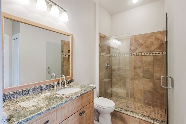 bathroom featuring vanity, toilet, and a shower with door