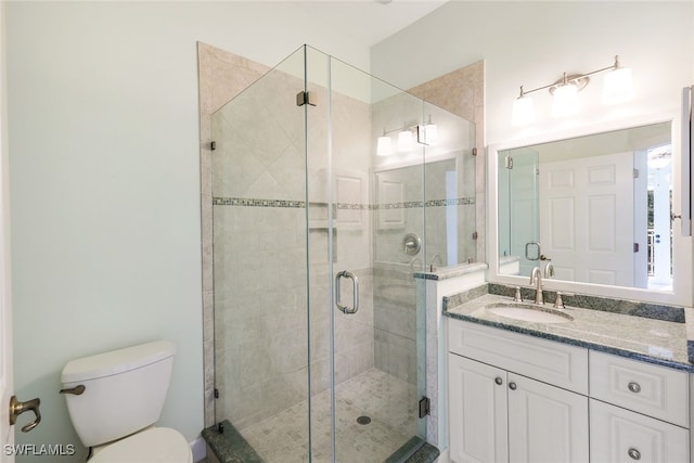 bathroom featuring vanity, toilet, and a shower with door