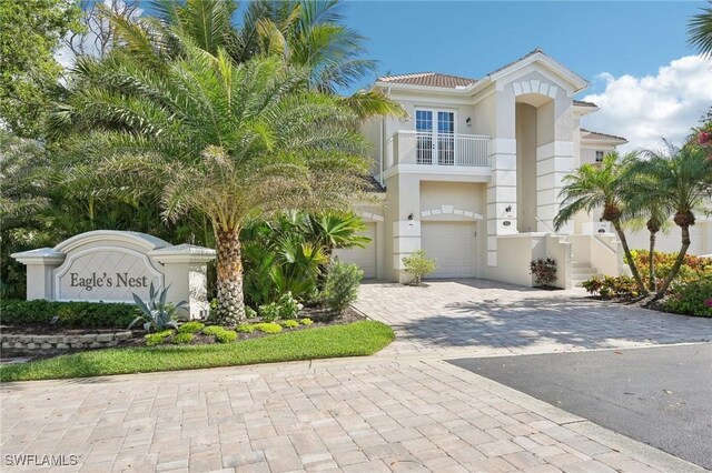 25970 Nesting Ct Unit 201, Bonita Springs, FL 34134 - view of front of home featuring a balcony, decorative driveway, an attached garage, stucco siding, and a tiled roof