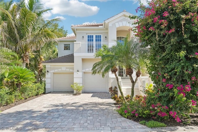 25970 Nesting Ct Unit 201, Bonita Springs, FL 34134 - mediterranean / spanish house featuring a balcony, an attached garage, a tiled roof, decorative driveway, and stucco siding