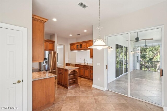 25970 Nesting Ct Unit 201, Bonita Springs, FL 34134 - kitchen with brown cabinetry, open shelves, light stone counters, a ceiling fan, and decorative light fixtures