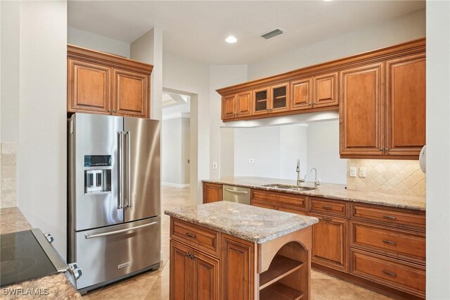 25970 Nesting Ct Unit 201, Bonita Springs, FL 34134 - kitchen featuring appliances with stainless steel finishes, a sink, brown cabinetry, light stone countertops, and recessed lighting