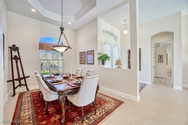 tiled dining area featuring a raised ceiling and ornamental molding