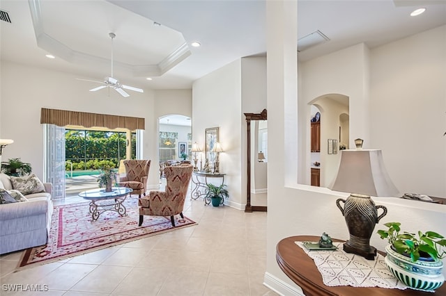 tiled living room featuring a high ceiling, a tray ceiling, and ceiling fan