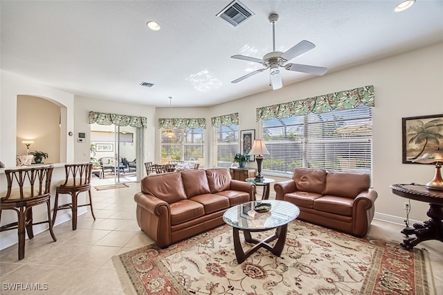 living room featuring light tile patterned floors, a healthy amount of sunlight, and ceiling fan with notable chandelier