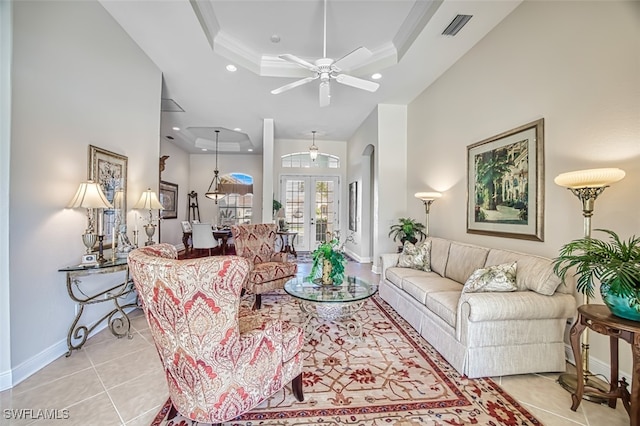 tiled living room with ceiling fan, a raised ceiling, ornamental molding, and french doors