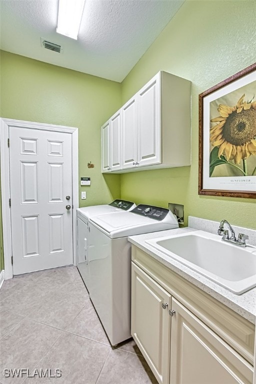 washroom with washing machine and clothes dryer, sink, cabinets, and a textured ceiling