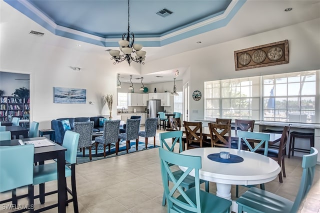 dining room featuring light tile patterned flooring, a raised ceiling, crown molding, and an inviting chandelier