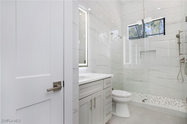 bathroom with tile patterned flooring, a tile shower, vanity, and toilet