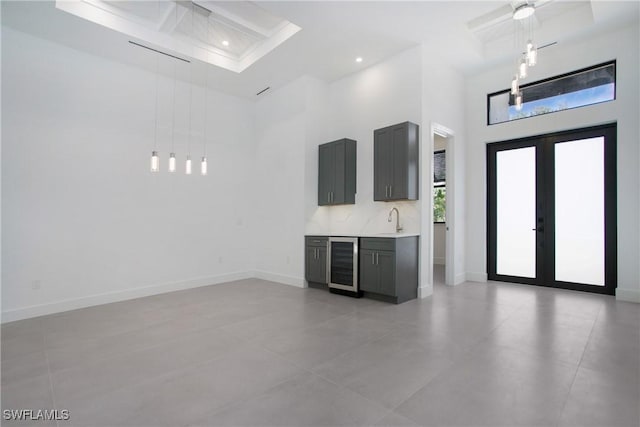 interior space featuring french doors, a towering ceiling, beverage cooler, and sink