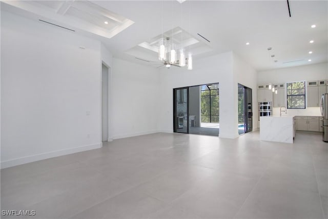 spare room featuring plenty of natural light, a towering ceiling, sink, and coffered ceiling