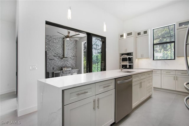 kitchen featuring stainless steel appliances, ceiling fan, a center island with sink, white cabinets, and hanging light fixtures