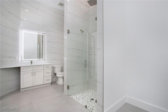 bathroom featuring tile patterned flooring, a shower with door, vanity, and toilet