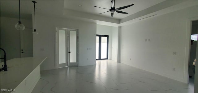 interior space featuring ceiling fan, a raised ceiling, and french doors