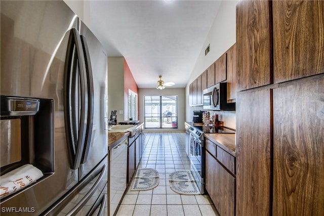 kitchen featuring stainless steel appliances, lofted ceiling, and light tile patterned flooring