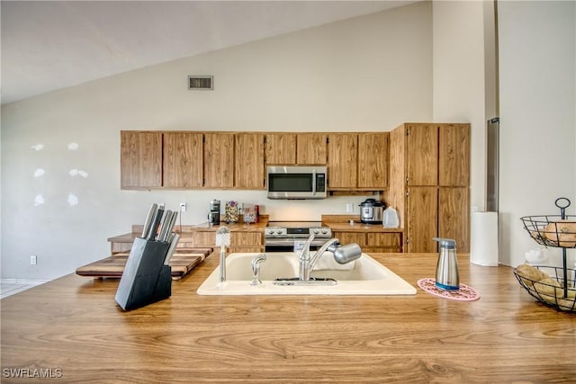 kitchen featuring appliances with stainless steel finishes and high vaulted ceiling