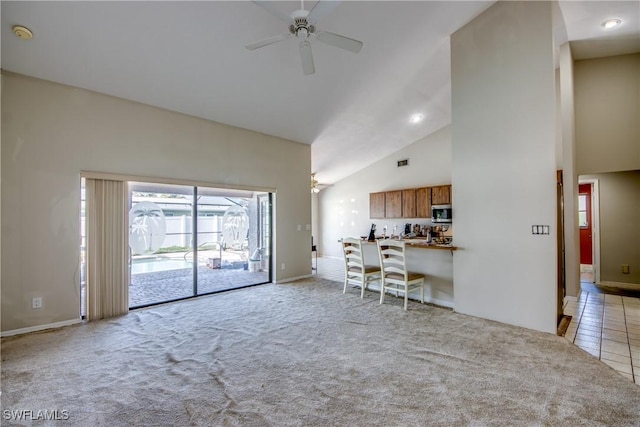 unfurnished living room with ceiling fan, high vaulted ceiling, and light colored carpet