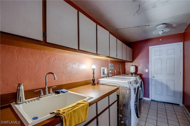 clothes washing area featuring washer and dryer, light tile patterned flooring, cabinets, and sink