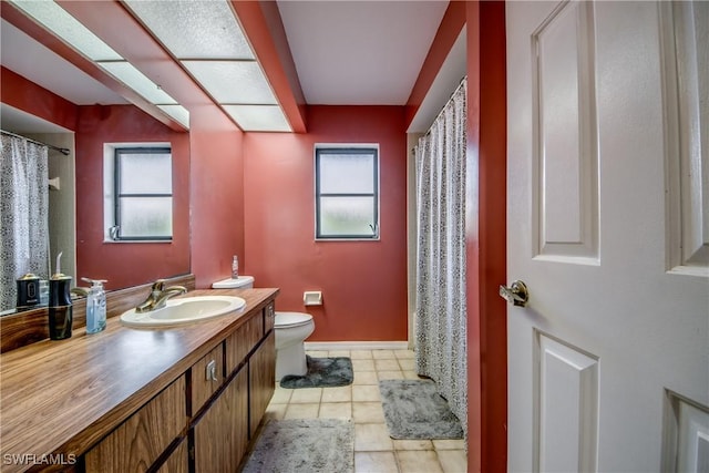 bathroom with toilet, vanity, tile patterned floors, and a healthy amount of sunlight