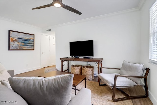 living room with wood-type flooring, ornamental molding, and ceiling fan